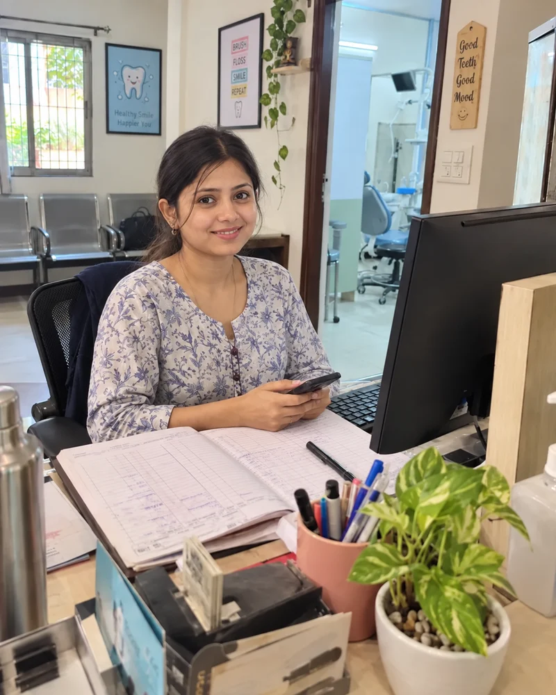 A smiling clinic receptionist looking toward the camera at the front desk.